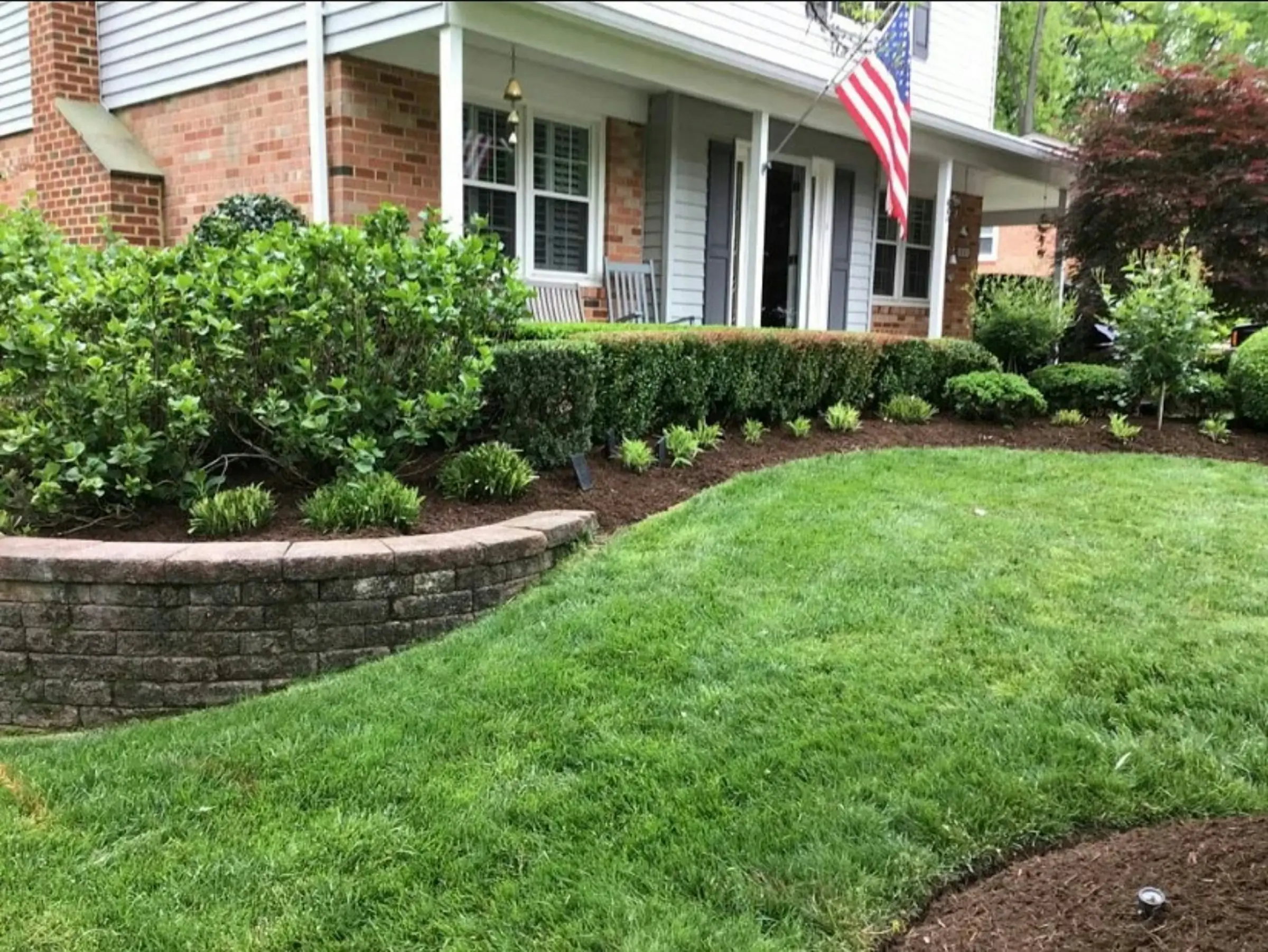 Freshly mulched landscape beds and a manicured lawn in front of a brick home