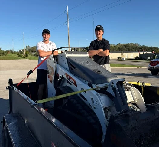 Braxton Vonnahme and Jack Badding with their compact track loader on a trailer