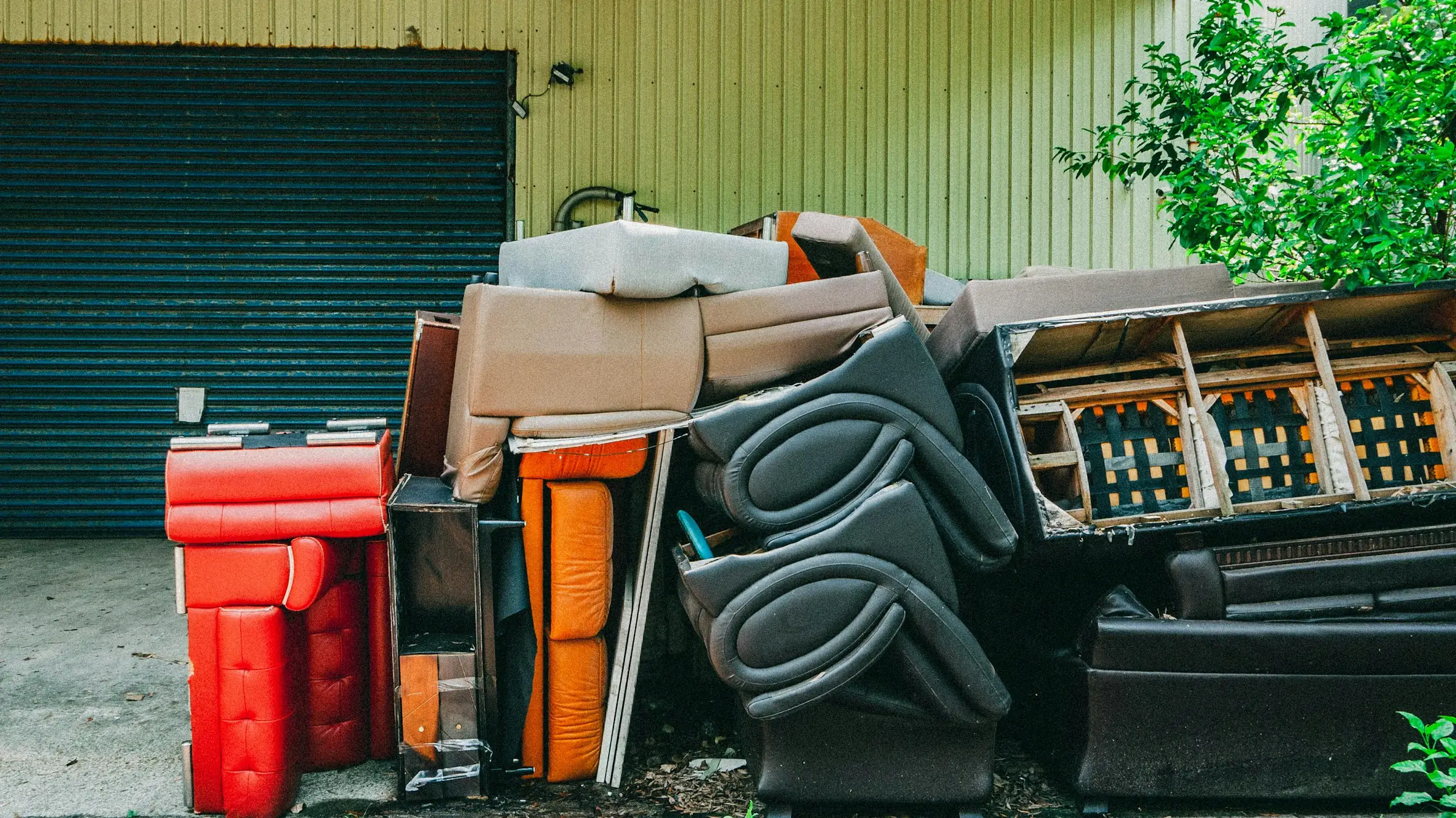 Pile of old couches, chairs, and furniture waiting to be hauled away