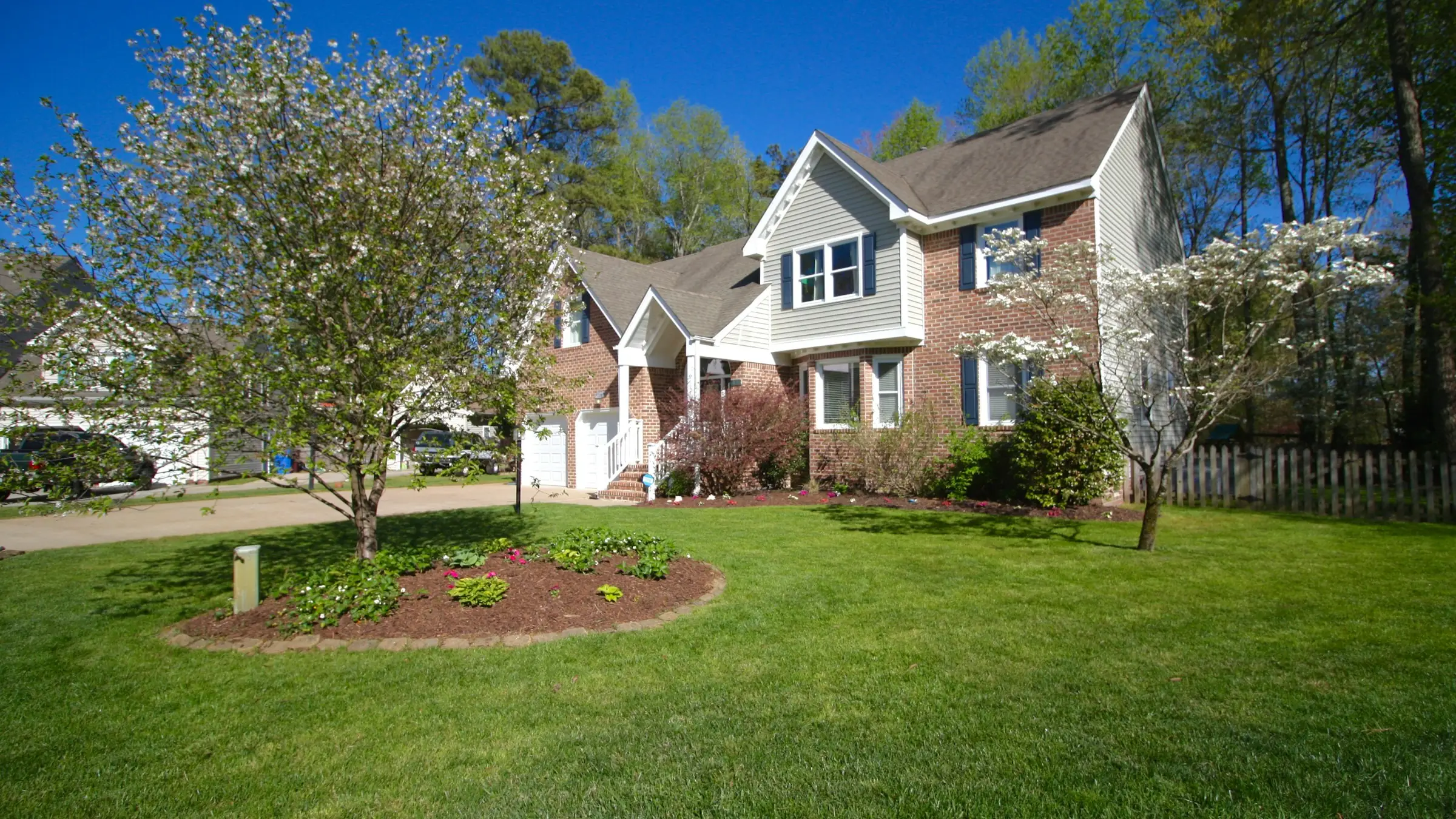 Brick home with a mulched tree ring, landscape beds, and a freshly mowed lawn